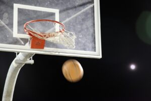 Basketball dropping toward a hoop under lights at night